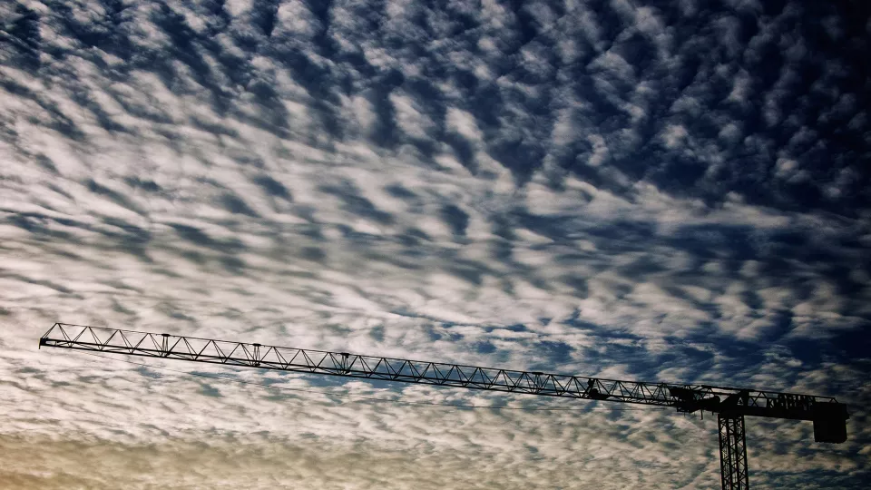 En byggarbetskran mot en himmel med moln. Foto.