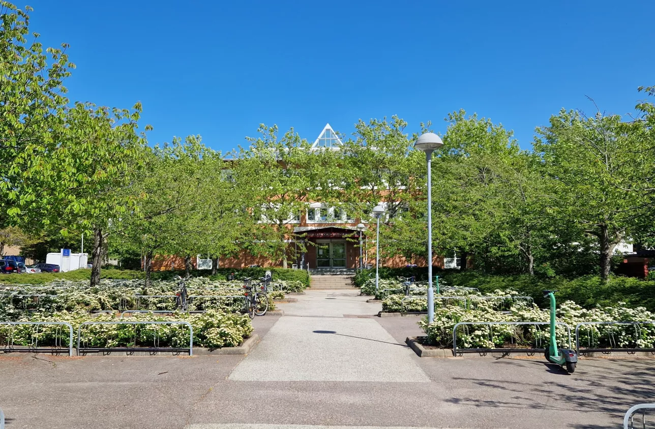 En bild på ekonomihögskolan byggnad 2. Blå himmel och gröna träd. 