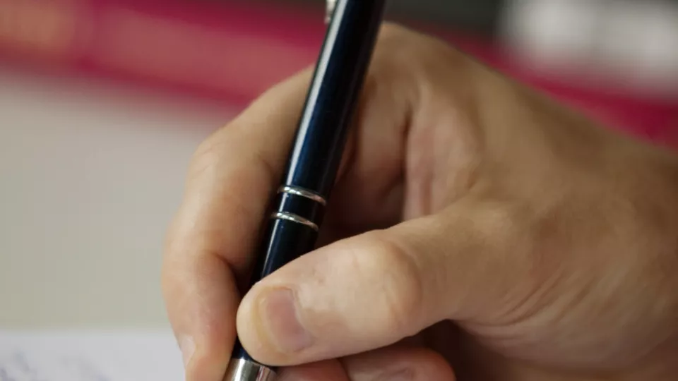En hand som håller en penna och skriver anteckningar på paper 