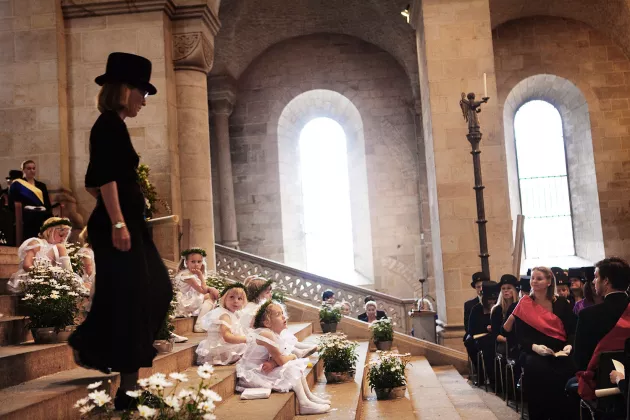 En kvinna klädd i svart går nerför trapporna i domkyrkan. Hon är omgiven av publik, både barn och vuxna.