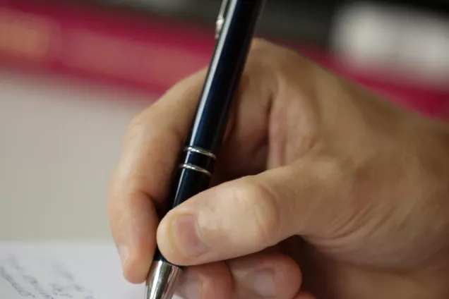 En hand som håller en penna och skriver anteckningar på paper 