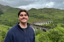 Fotografi på Fredrik framför ett grönt landskap.