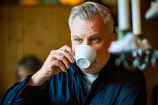 En man dricker kaffe.