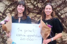 Två unga kvinnor håller en stor check på 20000 kronor