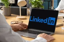 Person framför en bärbar dator med LinkedIns logotyp på skärmen. Foto.