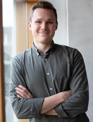 Porträttbild på man som ler och lutar sig mot ett fönster.  